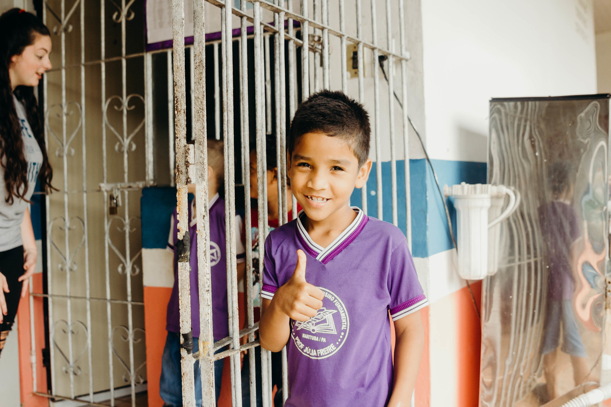 Brazilian Boy wearing a purple shirt and giving a thumbs up.